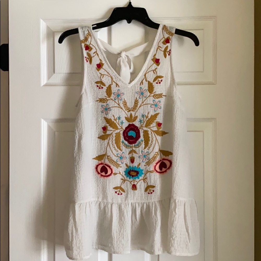 white top with embroidery and tie-back detail.